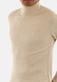 Maglione a collo alto di un beige chiaro, con un motivo a treccia testurizzato, design aderente e tessuto liscio con dettagli a coste sul collo e ai lati.