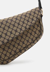 Brun lærredshåndtaske med navy blå geometrisk mønster, buet design og sort skulderrem. Har en fold-over klap med gulddetaljer.