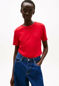Rood T-shirt met korte mouwen van een gladde katoenmix met een ronde hals. Gecombineerd met hoogwaisting blauwe spijkerbroek met een knoopsluiting.