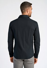 Schwarz langärmliges Hemd mit kragen, glatter Textur, Rückenpasse und knöpfbaren Manschetten, kombiniert mit hellgrauen Hosen.