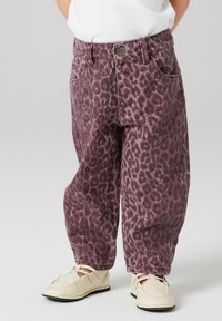 Violet leopardų rašto džinsai su laisvu siluetu, turintys mygtukų užsegimą ir du priekiniai kišeniai, derinami su šviesios spalvos batais.