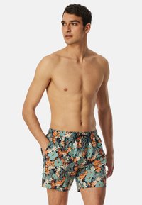 Heren zwembroek met een bloemenpatroon in groen, oranje en blauw. Elastische tailleband met trekkoord, zijzakken, tot halverwege de dij.