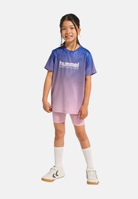 Sportig outfit med en gradiente blå till rosa kortärmad t-shirt med texten "hummel PERFORMANCE", tillsammans med rosa shorts och vita sneakers.