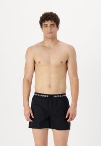 Črne bokserice z elastikami v pasu, s logotipom "JACK & JONES" v beli barvi. Narejene iz lahkega materiala z sproščenim krojem.