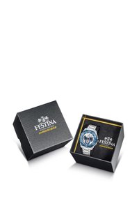 Sidabrinis metalinis laikrodis su mėlynu ciferblatu, esančiu juodame tekstūriniame kartoniniame dėkle. Ypatybės apima sidabro spalvos akcentus ir poliruotą giją.