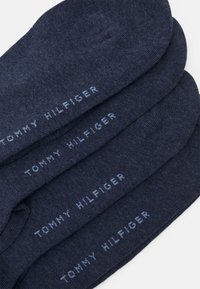 Marine sokker lavet af blødt stof, med en glat tekstur og mærkenavnet "TOMMY HILFIGER" vævet i lyseblå bogstaver.