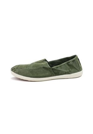 Zapatilla slip-on de lona verde con punta redondeada, paneles laterales elásticos y suela de goma blanca. Textura suave con un detalle minimal.