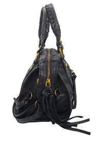 Sac à main en cuir noir avec quincaillerie dorée, fermeture éclair supérieure et poignées tressées. Caractéristiques de franges extérieures et d'une surface texturée. Forme compacte.