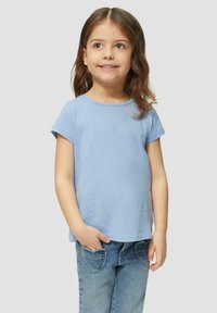 Helles blaues Baumwoll-T-Shirt mit kurzen Ärmeln, rundem Halsausschnitt und zwei gestickten Herzdetails nahe der Schulter. Kombiniert mit Jeans.