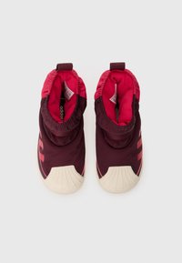 Ett par kastanjefärgade och rosa slip-on sneakers med vita gummiskalöppningar, elastiska anklar och synliga inre varumärkesetiketter.