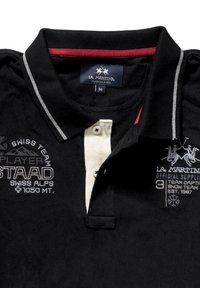 Svart pikétröja med röd krage, vit knappslå och broderade logotyper i grått och vitt. Gjord av bomull.