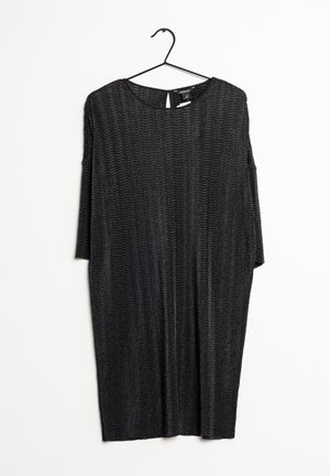 Vestido negro de manga corta con un ajuste holgado, que presenta un patrón texturizado y un escote redondo. Cuelga de una percha de plástico negra.