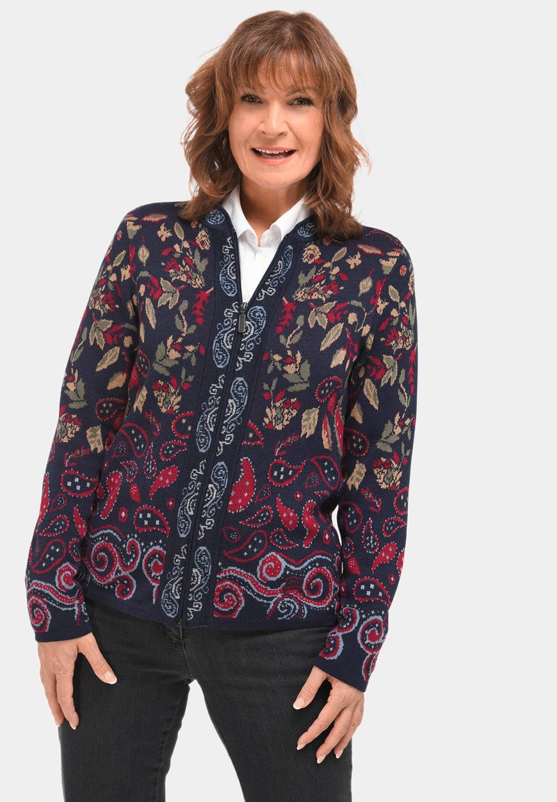 Marineblauwe cardigan met bloemen- en paisleypatronen in rood, groen en blauw. Voorzien van een ritsluiting en lange mouwen, gemaakt van een gestructureerde breimateriaal.