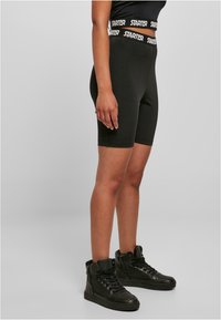 Shorts de vélo noirs avec une taille texturée arborant le logo "STARTER", associés à des baskets montantes noires.