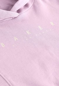 Svetloružová mikina s kapucňou vyrobená z mäkkého materiálu, s predným logom, na ktorom je napísané "BAKER" krémovým písmom. Hladká textúra, ležérny dizajn.
