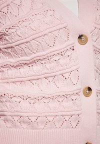 Cardigan di un rosa chiaro con intricati motivi a rombo, bordi a costine e grandi bottoni rotondi beige sul davanti.