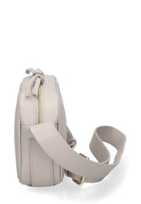 Borsa a tracolla in pelle beige con forma rettangolare, zip dorata e tracolla regolabile; presenta una texture liscia e un design minimalista.