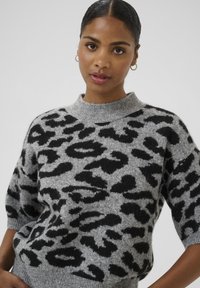Gray knitted sweater featuring a black animal print design, short sleeves, and a rounded collar. Textured fabric gives a cozy appearance.