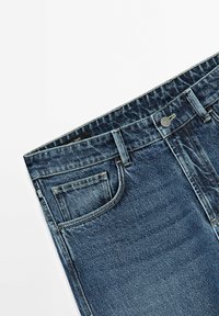 Tmavě modré džíny z denimu s klasickým pětipoklopovým designem, kovovým zapínáním na knoflík a jednoduchými stehy podél pasu.