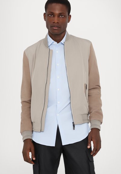 Leichte Bomberjacke in Beige und Braun mit glatter Oberfläche, gerippten Bündchen, Frontreißverschluss und Seitentaschen. Geschichtetes Design.