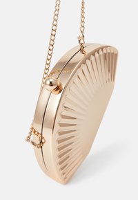 Metallic gold clutch bag with a fan-like ridged design, rounded shape, a short chain strap, and a spherical clasp closure.
