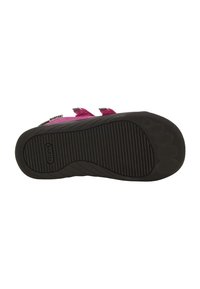 Suola di scarpa in gomma nera con scanalature testurizzate e motivi circolari rialzati; presenta cinturini rosa per una chiusura sicura.