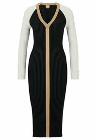 Robe côtelée avec un corps noir, des manches contrastantes blanches, et une rayure verticale dorée. Elle présente un col en V et des boutons décoratifs sur la manche.