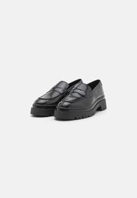 Sorte patent lær loafers med en tykk, teksturert såle. Har et quiltet overdelsdesign og glatt finish. Slip-on stil uten snøring.