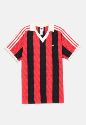 Chemise à manches courtes rayée verticalement rouge et noire avec col et poignets blancs, arborant un petit logo Adidas doré et des rayures rouges sur les manches.
