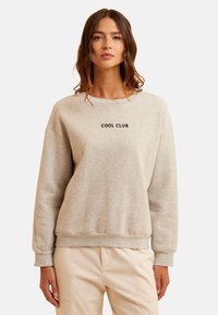 Sudadera de algodón de color gris claro con cuello redondo, hombros caídos, mangas con puños y el texto negro "COOL CLUB" en la parte frontal.