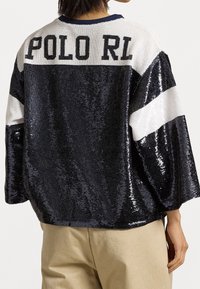 Černý a stříbrný přes oversized svetr s flitry, s nápisem "POLO RL", bílými pruhy na rukávech a kulatým výstřihem.