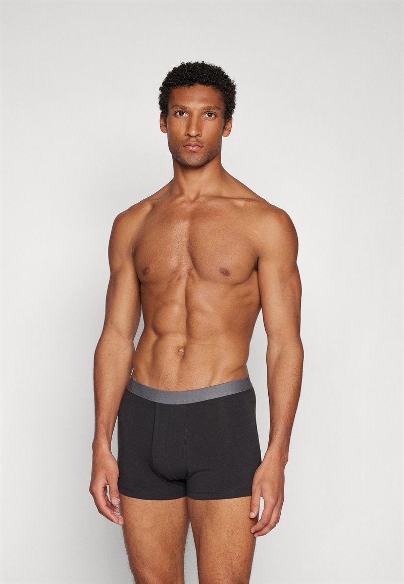 Schwarze Boxer-Shorts mit einem grauen elastischen Bund, aus einem glatten Material gefertigt, mit einer taillierten Passform und ohne sichtbare Muster.