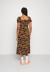 Abito floreale con sfondo nero, caratterizzato da fiori arancioni, viola e gialli. Maniche a sbuffo corte, scollatura quadrata e gonna di lunghezza media.