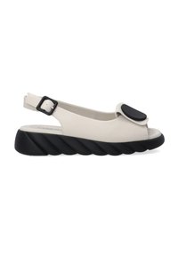 Beige slingback sandaal met een open teen, grote zwarte accenten en een getextureerde zwarte zool met een gedraaid patroon. Verstelbare gesp sluiting.