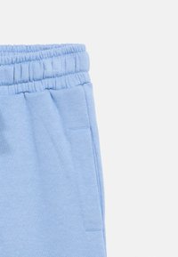 Calças de moletão azul clarinho com cintura elástica e bolsos laterais, apresentadas contra um fundo branco.