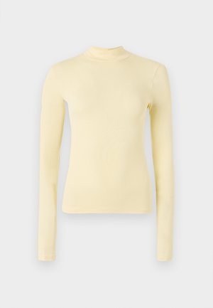 Dolga majica s turtleneck ovratom iz mehkega rumenega materiala, oprijetega kroja z visokim ovratnikom in gladko teksturo, brez vidnih vzorcev ali kovinskih elementov.
