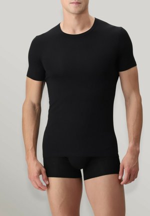 T-shirt aderente nero a maniche corte, realizzato in tessuto liscio, con scollatura rotonda. Abbinato a pantaloni corti aderenti neri.