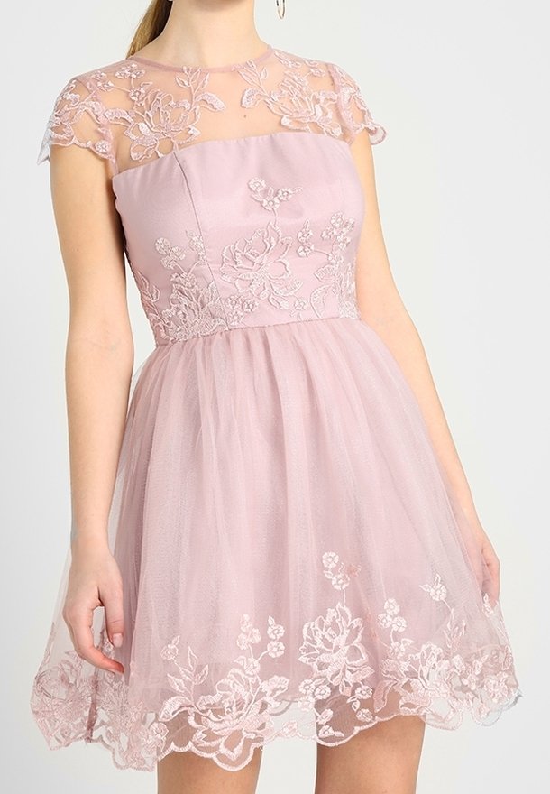 Robe rose avec un corsage ajusté et des manches courtes en dentelle florale transparente. Jupe en tulle avec des motifs floraux brodés sur l'ourlet.