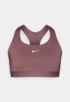 Lilla sports-bh med racerback-design, lavet af glat stof. Har en hvid Nike-logo og ventilationshuller nær kanten.