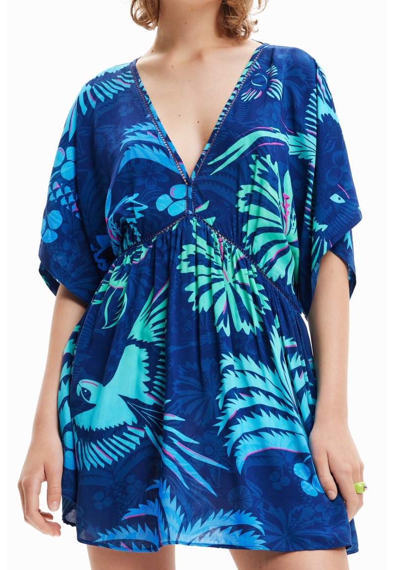 Robe tropicale à imprimé bleu avec un profond décolleté en V, des manches courtes et une taille froncée. Le tissu a une texture lisse avec des accents verts vifs.