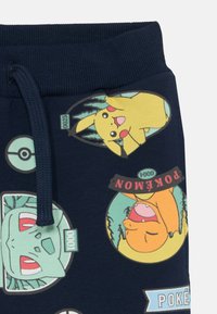 Námornícke joggery s elastickým pásom, s farebnými potlačami postáv Pokémon, ako sú Pikachu, Bulbasaur a Charmander.