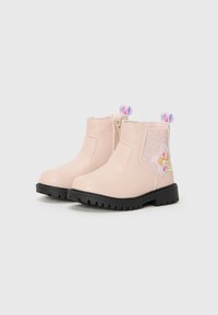 Bottines rose clair avec semelles noires, dotées d'une fermeture éclair sur le côté et d'un badge étoile décoratif sur le côté extérieur.