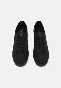 Zwarte canvas sneakers met vetersluiting, rubberen zolen en een subtiel logo op de tong. Kenmerken zijn een zachte textuur en een afgeronde neusvorm.