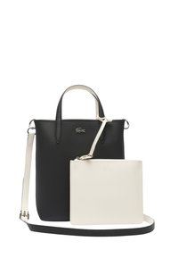 Sac fourre-tout synthétique noir texturé avec poignées doubles, une pochette en cuir blanc détachable et une bandoulière réglable. Détail du logo Lacoste.