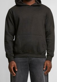 Tmavě šedá mikina s kapucí vyrobená z bavlněné směsi. Má přední kapsu na břiše, žebrované manžety a kapuci se šňůrkami. Jemná a hladká textura.