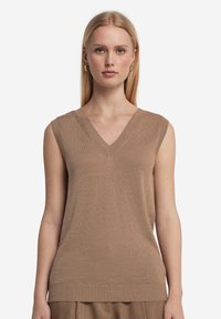 Beige ärmlös stickad topp med V-ringning, ribbat fåll och subtil textur. Enkel och mångsidig för lager-på-lager eller att bära ensam.