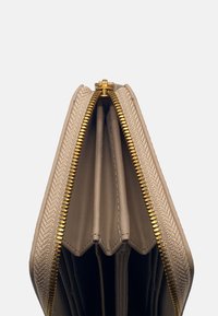 Beige ritsportemonnee met meerdere compartimenten, gouden hardware, gestructureerde buitenkant en gladde binnenvoering. Beschikt over een dubbele ritssluiting.