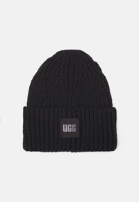 Cappello in maglia nera con risvolto, dotato di un'etichetta rettangolare nera con lettere bianche. Design a coste testurizzate in tutto il cappello.