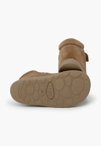 Botines de ante marrón con puntera redondeada, forro suave y suela de goma texturizada con patrones redondeados y marca en relieve.