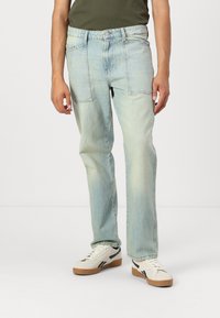 Svetlo modri jeans s sproščenim krojem, petimi žepi, gumbom za zapiranje in rahlim bledenjem za obrabljen videz. Združeni z belimi supergami.